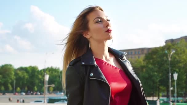 Hermosa mujer rubia con maquillaje brillante caminando bajo el sol en la calle de la ciudad — Vídeos de Stock