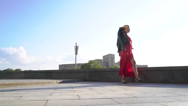 朝の日差しの中で街の通りを歩く明るい衣装でブロンドの女性モデル — ストック動画