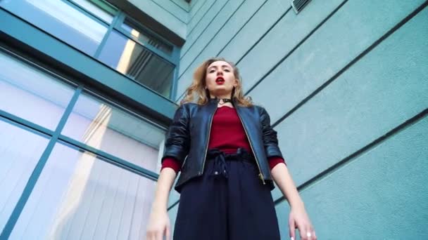 Low angle shot of young blonde woman standing against building and gesturing — Stock Video