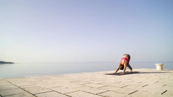 Atletisk kvinna bär sportkläder gör yoga på Seaside Boardwalk på morgonen — Stockvideo