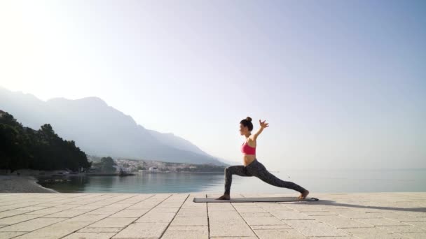 Mulher esportiva praticando ioga no calçadão à beira-mar com espaço livre e copiar — Vídeo de Stock