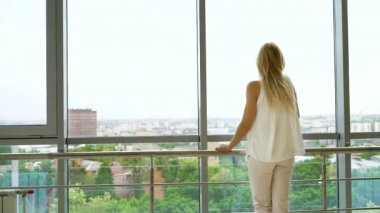 cityscape de pencereden dışarı bakan güzel sarışın kadının arka görünümü