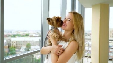 mutlu sarışın kadın elleri üzerinde küçük kabarık köpek yavrusu tutarak ve öpüşme