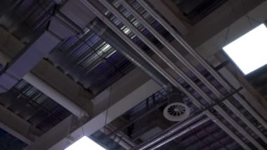 büyük alışveriş merkezinin tavanına monte edilmiş iklimlendirme sistemi ve lambaların metal boruların düşük açısı