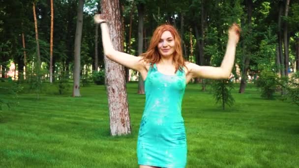 Rudowłosy młoda kobieta w mokrej sukni i Holi farby śmieje się i skoki w parku — Wideo stockowe