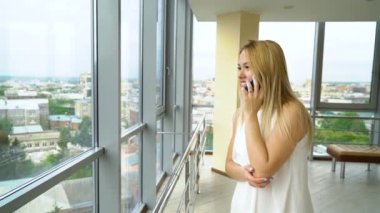 güzel genç kadın telefonda konuşuyor ve sonra büyük pencereden bakarak kapatır