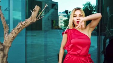 ağaçların yakınındaki cam yüzeylere karşı dans sevimli sarışın kadın