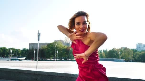 Rubia mujer en vestido rojo bailando sensualmente fuera en cámara lenta — Vídeo de stock