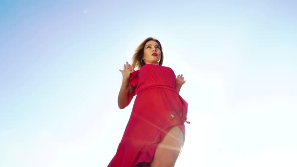 低角度拍摄有吸引力的金发女郎在红色礼服跳舞对蓝天 — 图库视频影像