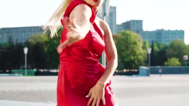 Великолепная блондинка в красном платье танцует на улице в замедленной съемке — стоковое видео