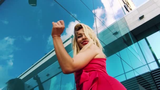 Angle bas de dame blonde dansant en rouge contre le mur miroir réfléchissant ciel bleu — Video