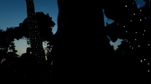 Низкий угол силуэтов людей на закате в городском парке во время пивного фестиваля — стоковое видео