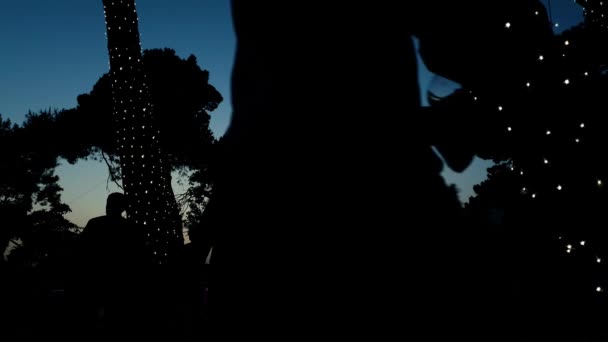 Faible angle de silhouettes de personnes au coucher du soleil dans le parc urbain pendant le festival de la bière — Video