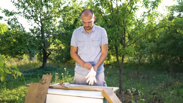 Vousatý muž si klade ochranné brýle a rukavice a začal zpracovávat dřevo — Stock video