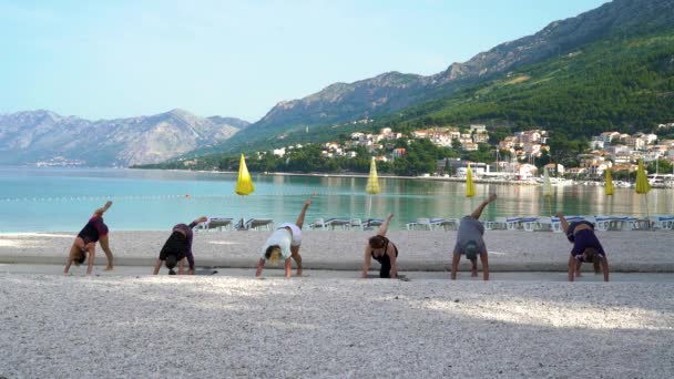 Practicing yoga at beautiful adriatic seaside with mountains on background — Stock Video