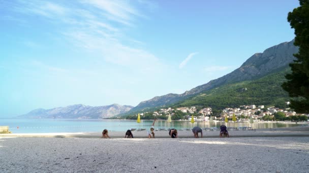 Йога класс на красивом Адриатическом побережье с горами на заднем плане — стоковое видео