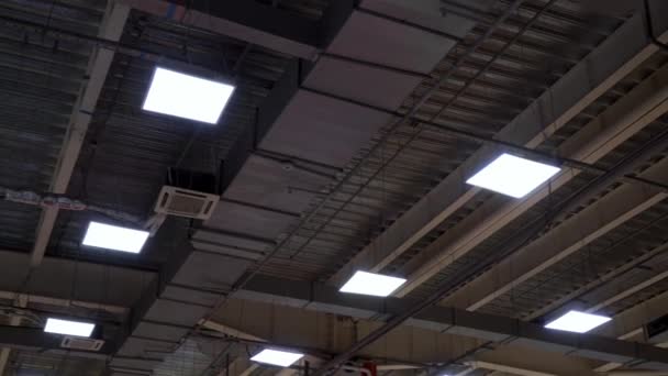 Long pipes of hvac system and lamps hang on ceiling of big mall — Stock Video