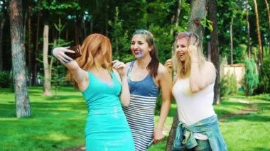üç genç kadın Holi boyalar sarılmak ve akıllı telefonda selfie fotoğraf yapma gülmek