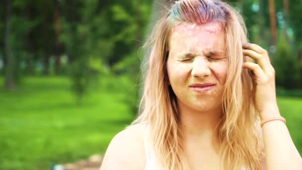 그녀의 얼굴과 머리카락에 홀리 페인트와 함께 웃는 금발 소녀의 초상화 — 비디오
