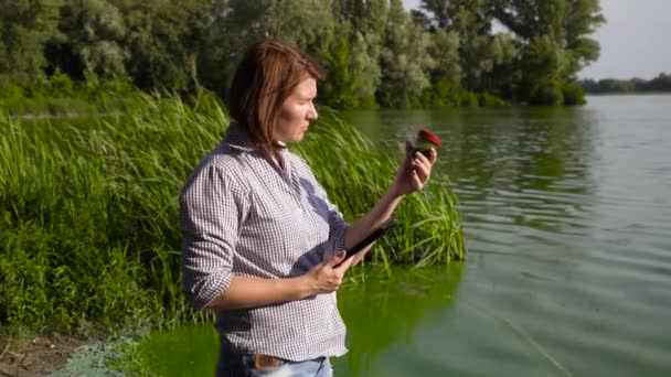 Взрослая женщина-эколог изучает образец зеленых водорослей и вводит данные о таблетках — стоковое видео