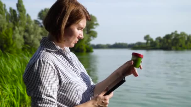 Side view of ecologist examining green algae sample and entering data on tablet — Stock Video