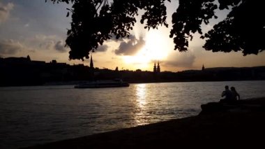 gün batımında nehir iskelesi üzerinde şarap ile piknik romantik çift siluet