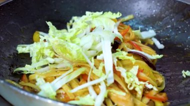 closeup kızartma tavasına yemek için doğranmış lahana ve maydanoz ekleyerek ve atmak