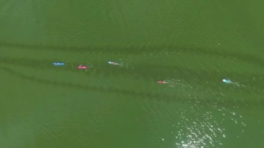 koyu yeşil nehir üzerinde kayakçılar ve Sup yatılı su yarışı havadan yukarıdan aşağıya
