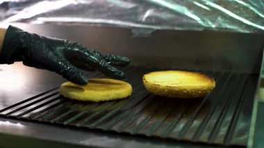 sırt yüzeyinde ızgara susam ile burger çörekler dönüm closeup şef el