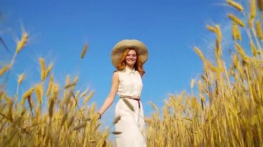 buğday alanında hareketli kamera doğru yürüyen kırmızı saçlı kadın düşük açı çekim