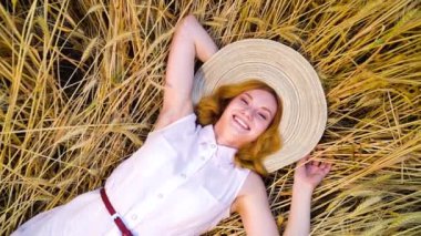 yukarıdan aşağıya kamera buğday tarlasında yatan ve kameraya gülen kadın üzerinde spin