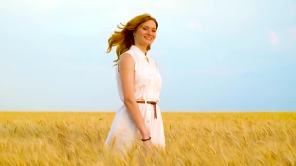 Красива жінка посміхається на камеру, ховається в пшеничному полі, а потім стрибає вгору — стокове відео