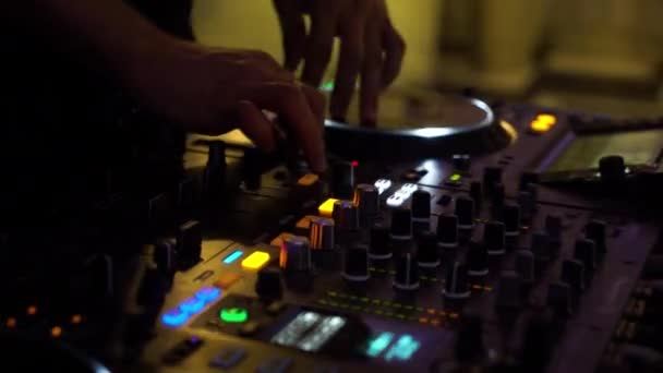 Gece kulübünün renkli ışıklarında mikser üzerinde çalışan disk jokey ellerin yakın çekim — Stok video