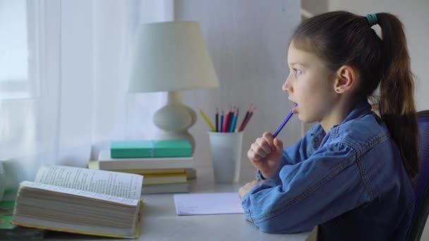 Маленька школярка жує ручку і розраховує на пальці під час виконання домашнього завдання — стокове відео