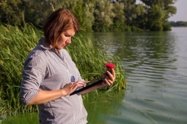 tablet üzerinde nehiralınan yeşil yosun hakkında bilgi girerek kadın ekolojist