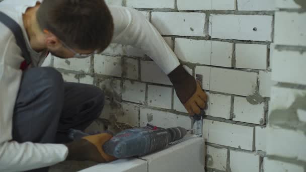 Constructeur faisant des trous dans le mur de briques avec perceuse électrique pour fixer pince de jonction — Video