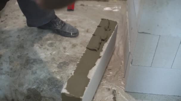 Plan à angle élevé des mains du constructeur dans les gants mettre mélangeur sur les côtés du bloc — Video