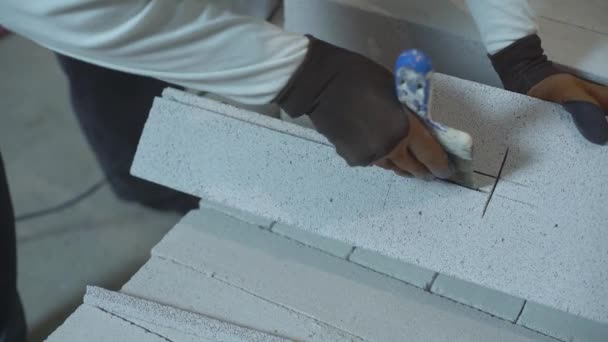 Blick auf Bauarbeiter Hände entfernen übermäßige Teile des Blocks mit Bauspachtel — Stockvideo