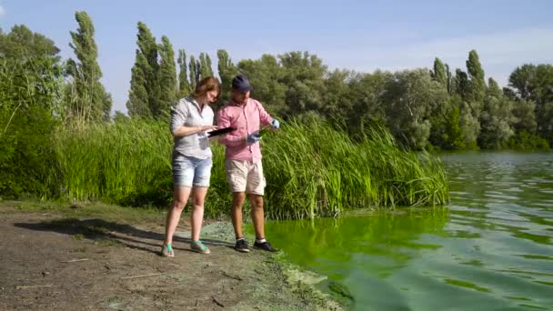 Ecologen onderzoeken groene algen monster genomen in rivier en voer gegevens op Tablet — Stockvideo