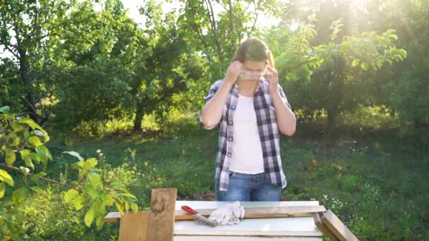 Kézműves nő helyezi a védőszemüveget és a kesztyűt a feldolgozás előtt fa deszka — Stock videók