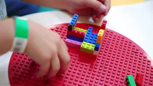 प्ले टेबलवर रंगीत प्लास्टिक ब्लॉक्स खेळत मुलाचे हात बंद — स्टॉक व्हिडिओ