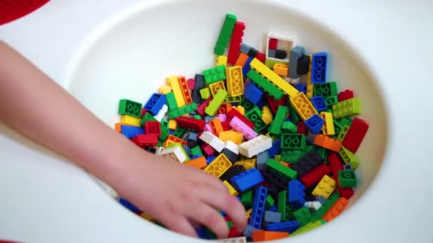 Primer plano de los niños preescolares manos recogiendo pequeños bloques de plástico de la mesa — Vídeos de Stock