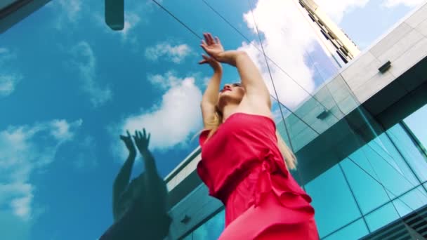 Niedriger Winkel des erotischen Tanzes einer blonden Frau im roten Kleid, die auf der Straße auftritt — Stockvideo