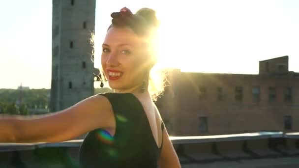 Retrato de mujer joven mirando a la cámara y bailando en el techo al atardecer — Vídeos de Stock