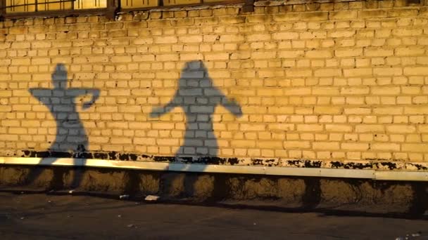 Dos siluetas femeninas bailando contra la pared de ladrillo en el techo al atardecer — Vídeos de Stock