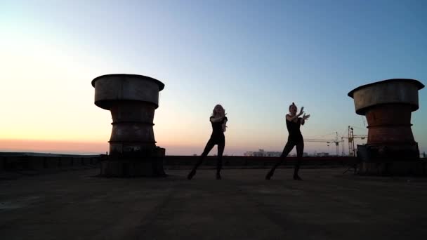 Siluetas de mujeres bailando al atardecer en el techo con arco iris en el fondo — Vídeos de Stock