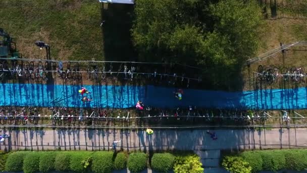 Сверху вниз триатлонные гонщики бегают на синем коврике и берут свои велосипеды — стоковое видео
