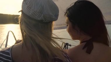 gün batımında nehirde yüzen yelkenli üzerinde sarılma lezbiyen çift arka görünümü