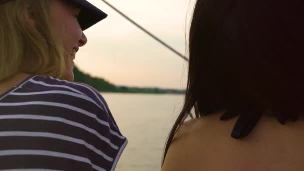 Achteraanzicht van twee vrouwen chatten tijdens het zeilen op boot bij zonsondergang — Stockvideo