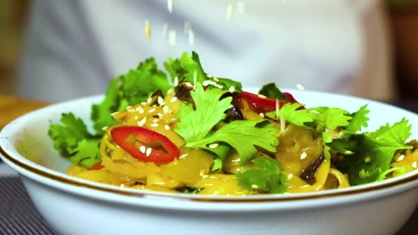 Крупный план добавления семян кунжута в блюдо с макаронами и овощами — стоковое видео